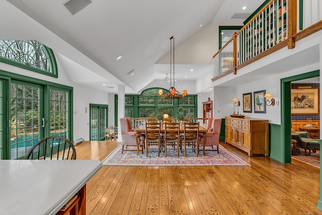 dining space featuring light wood finished floors, baseboard heating, recessed lighting, and high vaulted ceiling