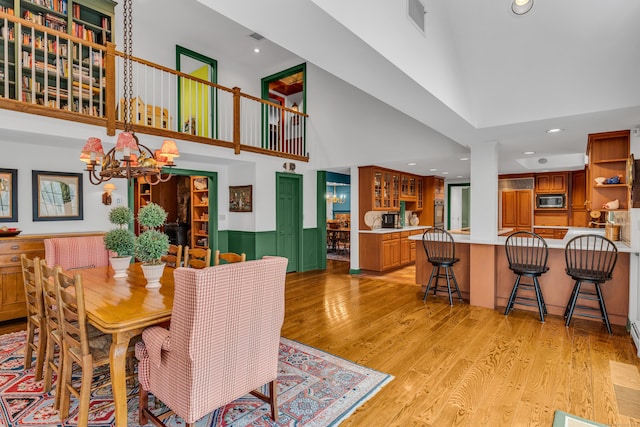 dining space featuring a notable chandelier, recessed lighting, light wood-type flooring, and a towering ceiling