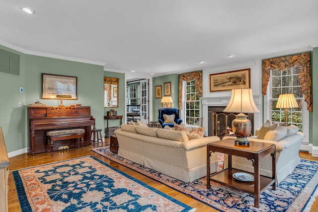 living area featuring recessed lighting, wood finished floors, a lit fireplace, and ornamental molding