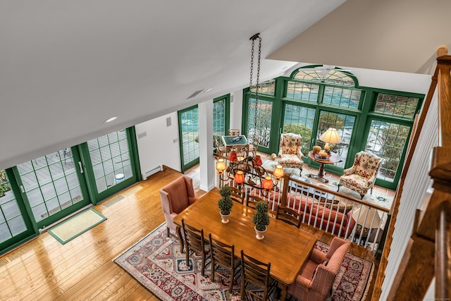 dining room with a baseboard radiator, lofted ceiling, and hardwood / wood-style flooring