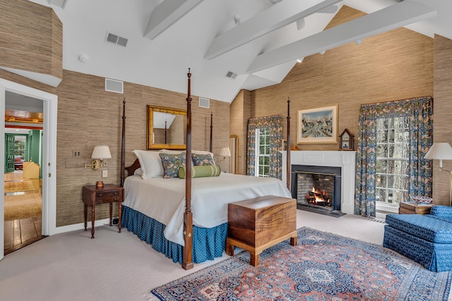 bedroom with beam ceiling, carpet flooring, visible vents, and a fireplace with flush hearth