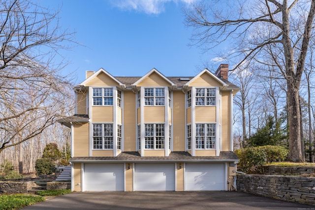 traditional-style house featuring a garage, driveway, and a chimney