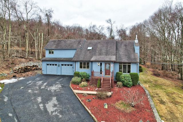 view of front of home featuring a garage, driveway, a shingled roof, and a front yard