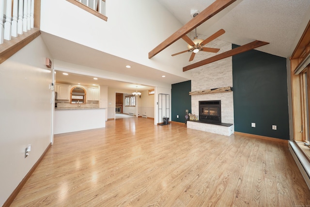 unfurnished living room with baseboards, a baseboard radiator, a stone fireplace, light wood-style floors, and high vaulted ceiling