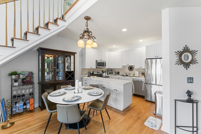 dining area with light wood-style floors, stairway, a chandelier, and recessed lighting