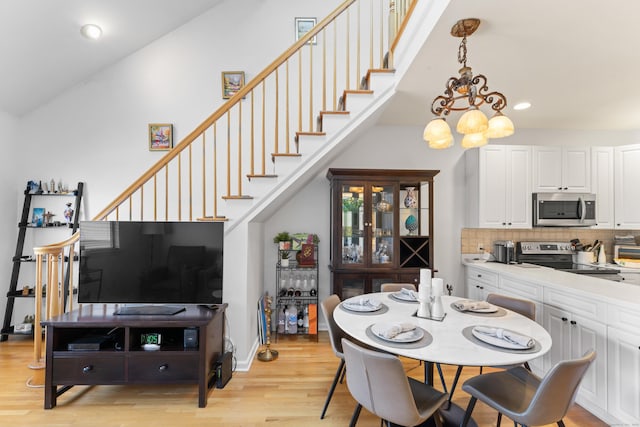 dining area with light wood finished floors, baseboards, stairs, a chandelier, and recessed lighting