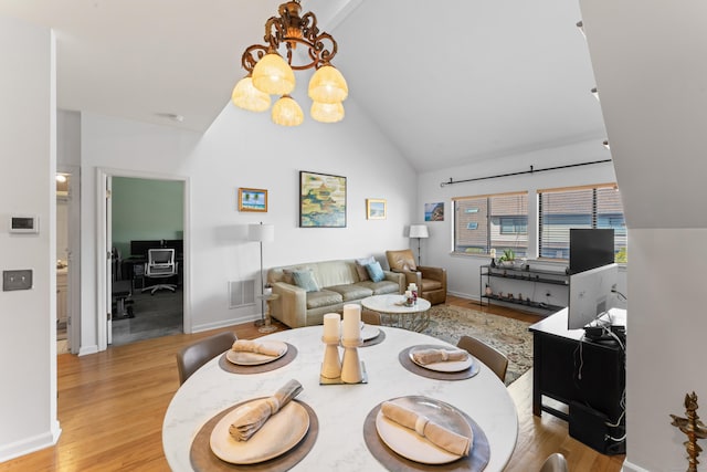 dining area with high vaulted ceiling, visible vents, baseboards, light wood finished floors, and an inviting chandelier