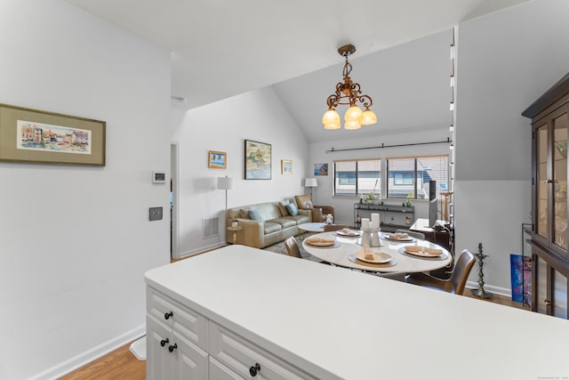 dining space featuring visible vents, baseboards, lofted ceiling, light wood-style floors, and a notable chandelier