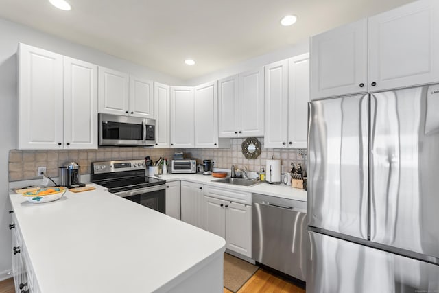 kitchen featuring appliances with stainless steel finishes, white cabinets, a sink, and tasteful backsplash