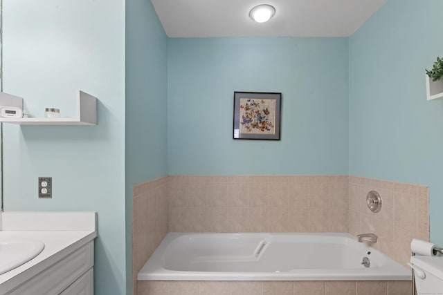 full bath featuring toilet, a garden tub, and vanity