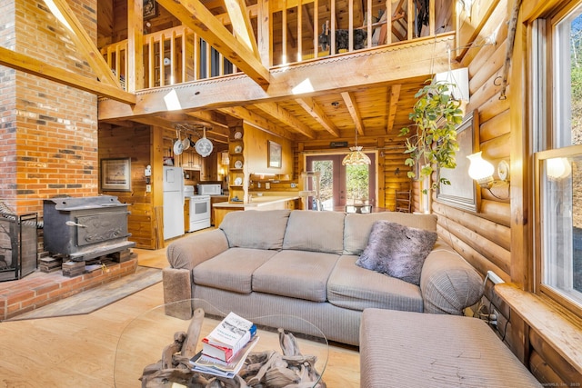 living area featuring wooden ceiling, a wood stove, beamed ceiling, and a high ceiling