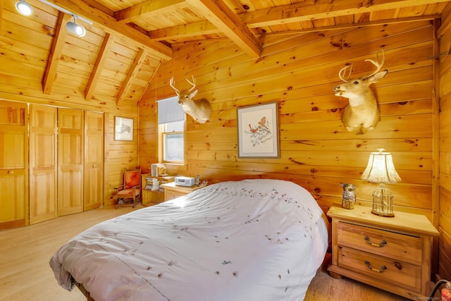 bedroom featuring lofted ceiling with beams, a closet, wooden walls, light wood finished floors, and wood ceiling