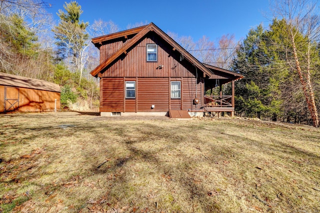 back of house featuring an outbuilding and a lawn