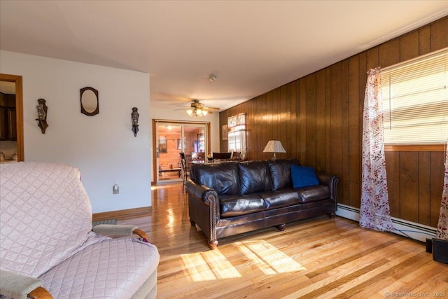 living area with a ceiling fan, wood walls, a wealth of natural light, and light wood-style floors