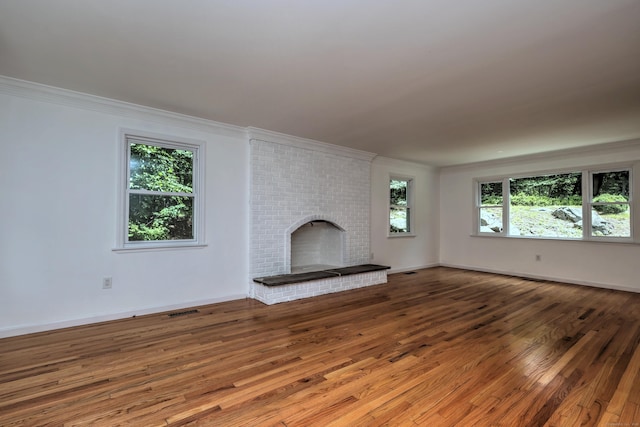 unfurnished living room with plenty of natural light, visible vents, wood finished floors, crown molding, and a fireplace