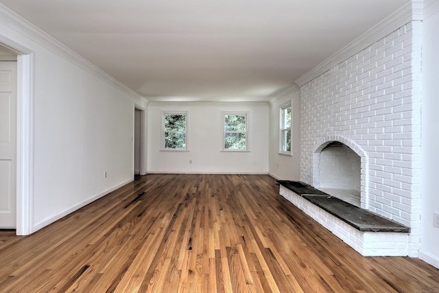 unfurnished living room featuring a brick fireplace, baseboards, ornamental molding, and wood finished floors