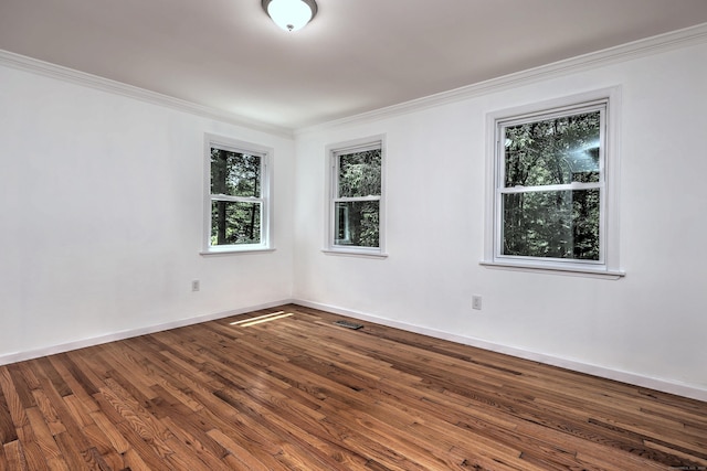 spare room featuring ornamental molding, wood finished floors, visible vents, and baseboards