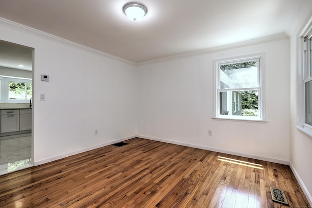 spare room featuring baseboards, visible vents, crown molding, and hardwood / wood-style floors