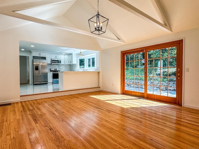 unfurnished living room with a chandelier, visible vents, a sink, and light wood finished floors