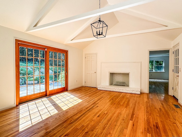 unfurnished living room featuring visible vents, wood finished floors, beamed ceiling, a fireplace, and a chandelier