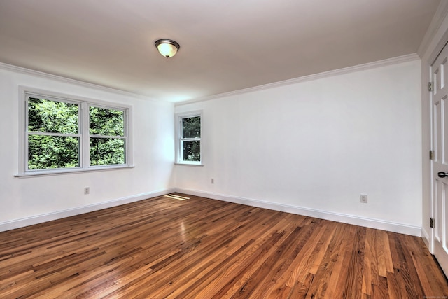 spare room featuring crown molding, baseboards, and wood finished floors