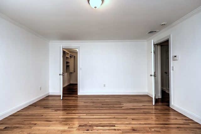 empty room with crown molding, baseboards, and wood finished floors