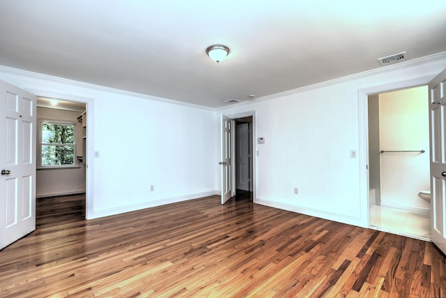 unfurnished room with visible vents, crown molding, baseboards, and wood finished floors