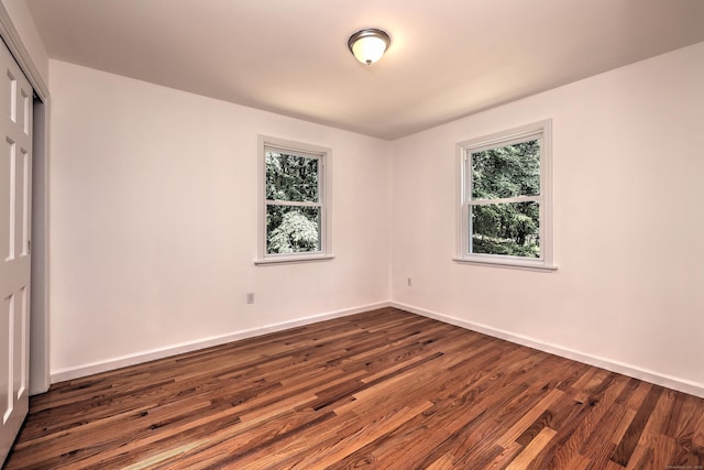 spare room with dark wood-style floors and baseboards