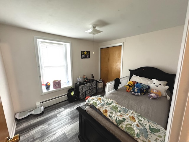 bedroom with a baseboard heating unit and wood finished floors