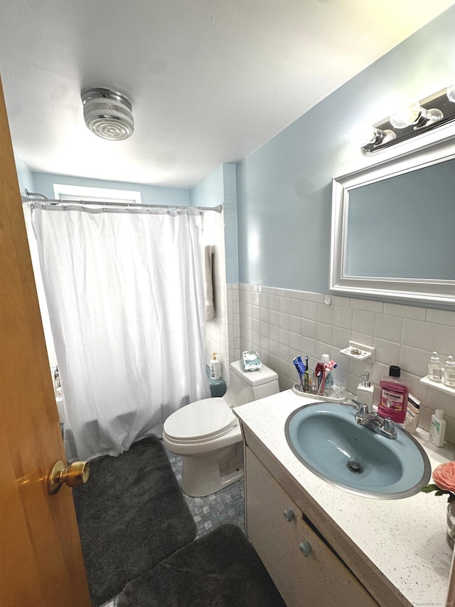 bathroom featuring toilet, a shower with curtain, a wainscoted wall, vanity, and tile walls