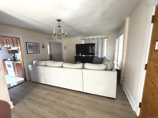 living room with baseboards, wood finished floors, and a notable chandelier