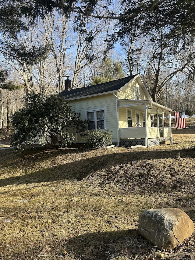 view of side of home featuring covered porch and a chimney