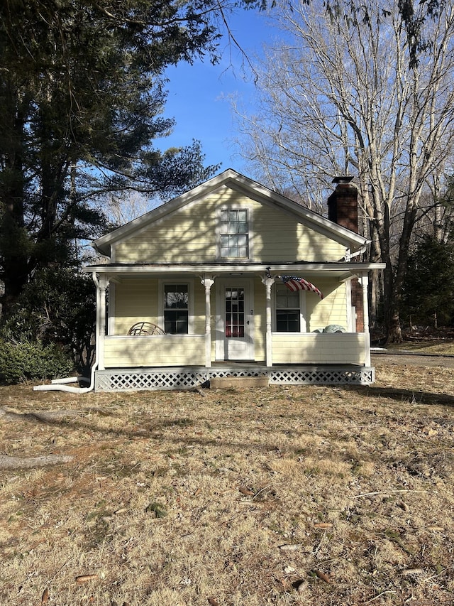 view of front facade featuring covered porch and a chimney