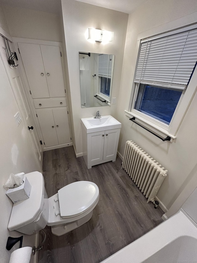 bathroom featuring toilet, wood finished floors, vanity, baseboards, and radiator