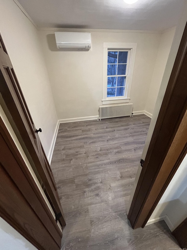 unfurnished room featuring baseboards, an AC wall unit, ornamental molding, radiator, and dark wood-style floors