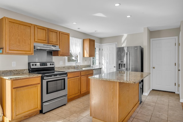 kitchen with light tile patterned floors, appliances with stainless steel finishes, light stone counters, a center island, and under cabinet range hood