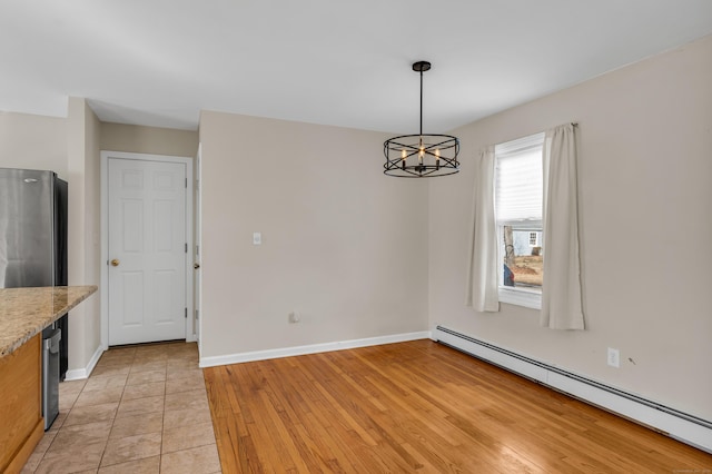 unfurnished dining area with an inviting chandelier, baseboards, a baseboard heating unit, and light wood-style floors