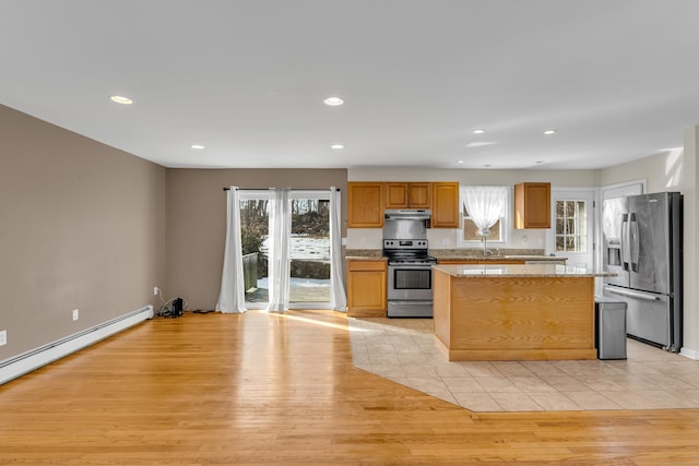 kitchen with light wood finished floors, stainless steel appliances, recessed lighting, a kitchen island, and under cabinet range hood