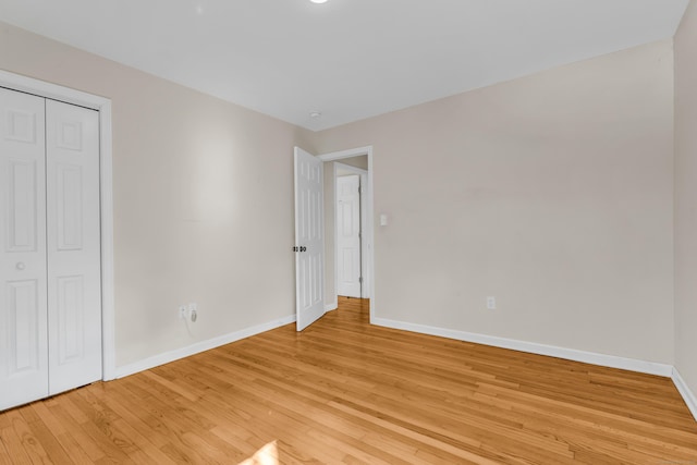 unfurnished bedroom with light wood-type flooring, a closet, and baseboards