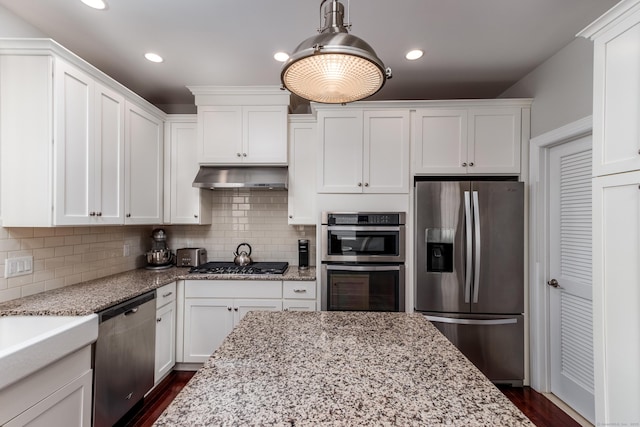 kitchen featuring stainless steel appliances, white cabinets, under cabinet range hood, and decorative backsplash