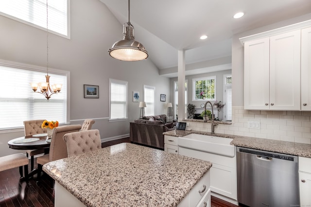 kitchen with lofted ceiling, a healthy amount of sunlight, a kitchen island, a sink, and dishwasher