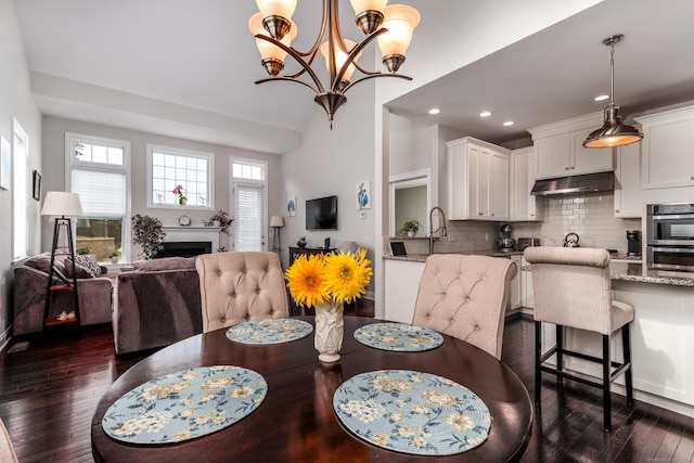 dining area featuring a chandelier, recessed lighting, a fireplace, and dark wood finished floors