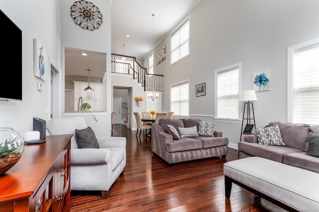 living area with a high ceiling, dark wood-style flooring, and baseboards