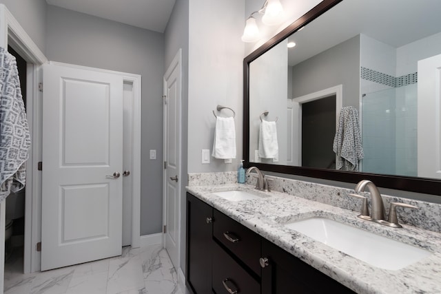 full bathroom featuring marble finish floor, double vanity, a sink, and baseboards