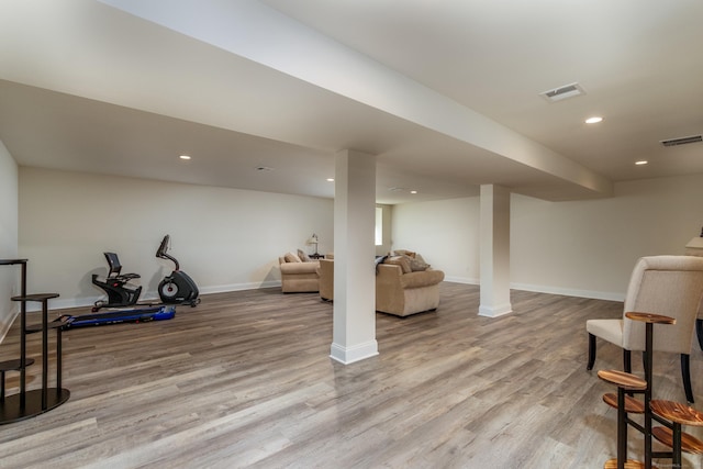 exercise area with wood finished floors, visible vents, and baseboards