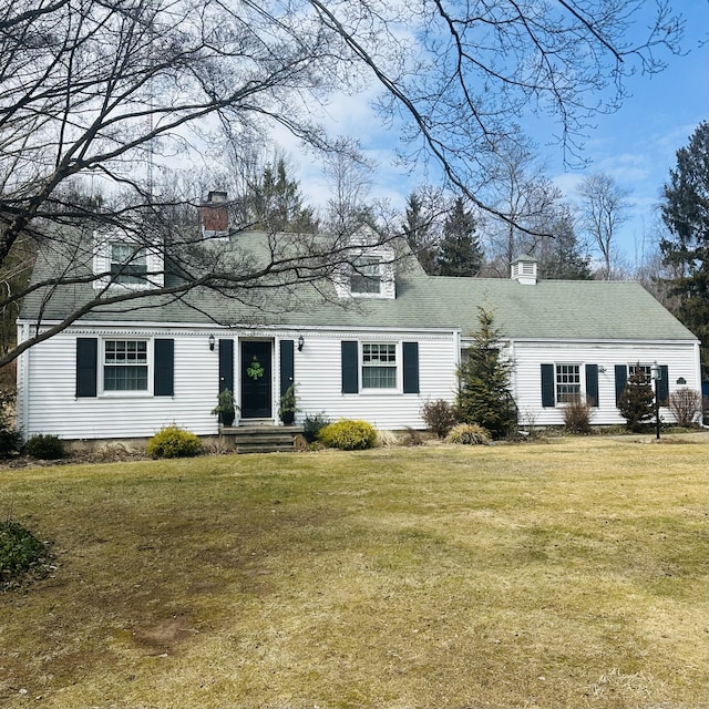 cape cod home with a chimney and a front yard