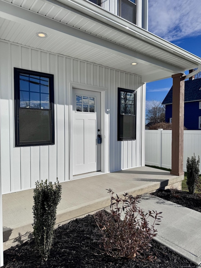 doorway to property featuring board and batten siding and fence