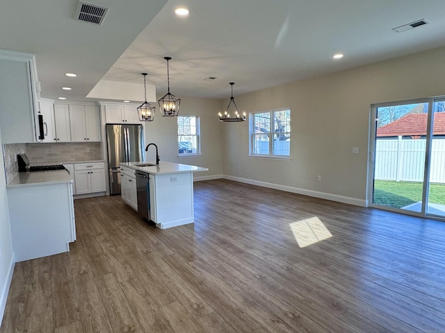 kitchen featuring dark wood-style floors, stainless steel appliances, visible vents, open floor plan, and a sink