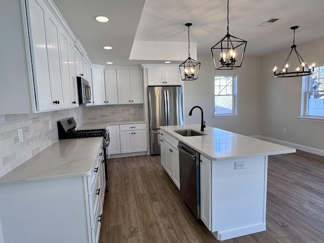 kitchen with stainless steel appliances, tasteful backsplash, visible vents, dark wood-type flooring, and a sink