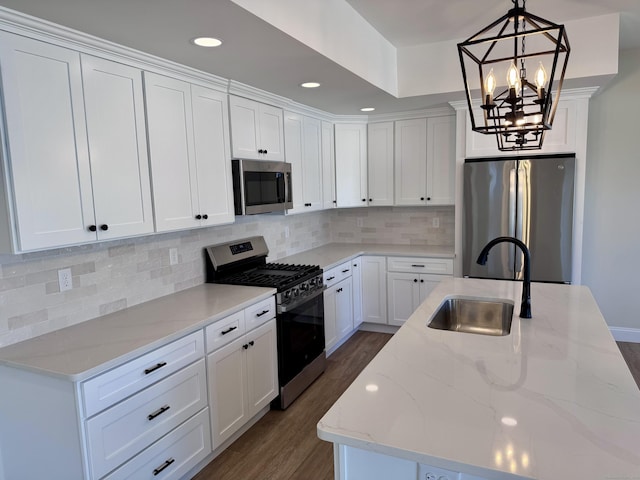 kitchen featuring dark wood finished floors, decorative backsplash, appliances with stainless steel finishes, white cabinetry, and a sink